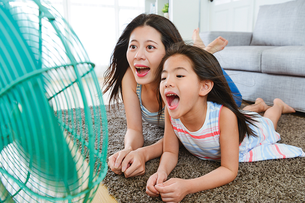 Mother daughter lying in front of fan