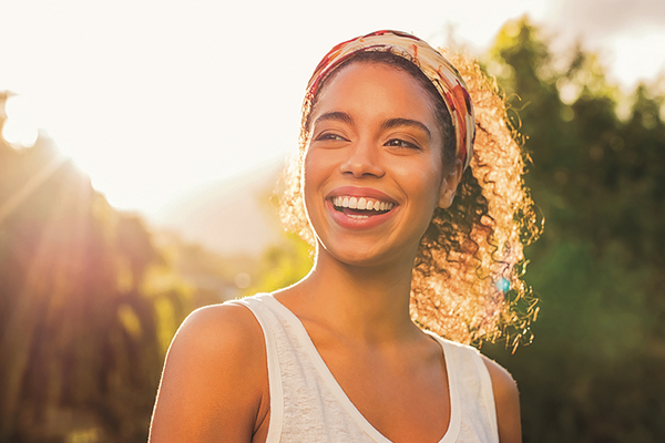 Person standing outside in sunshine smiling looking happy