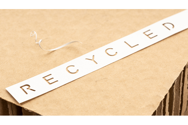 A piece of construction paper with the wrod RECYCLED cut out