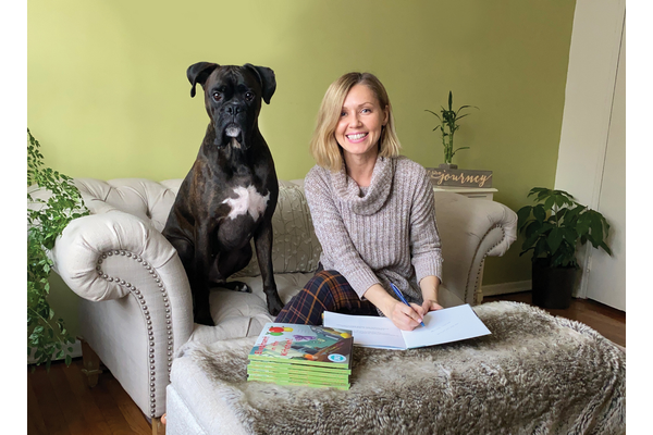 Aleksandra Starling posing with her big black dog sitting on the couch