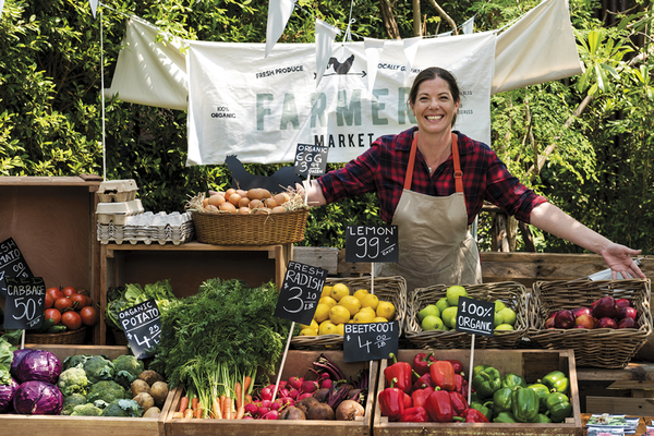 Person working food stand at farmer's market selling fruits and vegetables