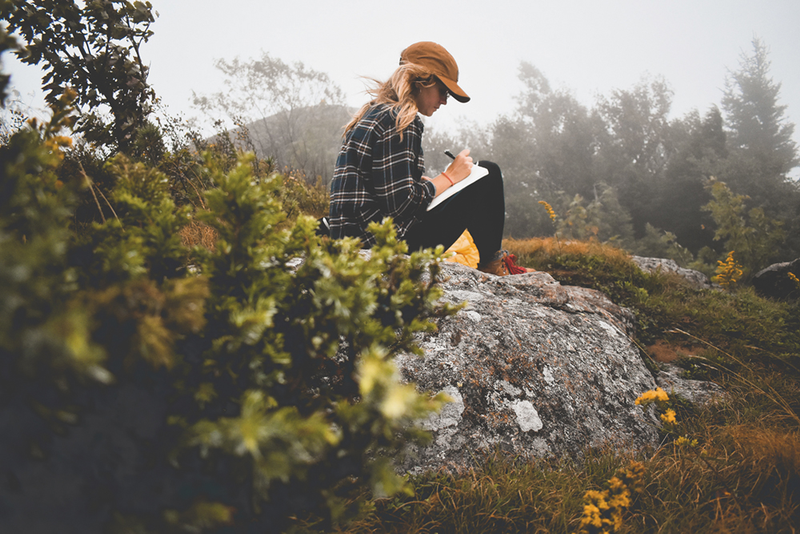 Person sitting in nature writing in journal