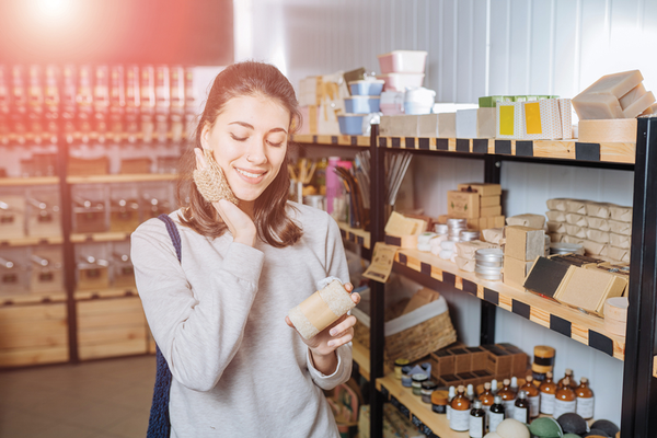 Person shopping green packaged personal care items in store holding skin scrubber to face