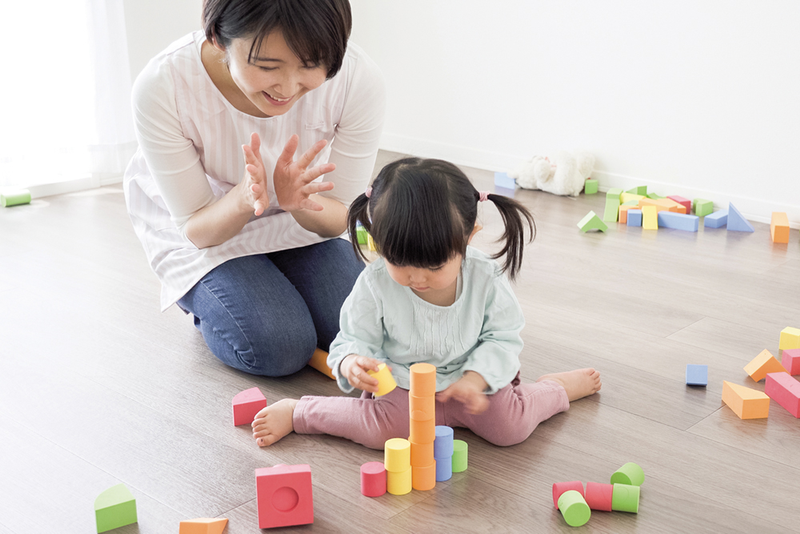 Parent clapping hands praising child building with blocks