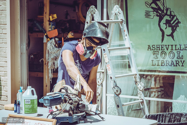 Person using tools wearing protective gear standing outside of Asheville Tool Library